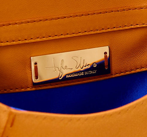Person wearing gloves holding a brown leather wallet with gold accents.