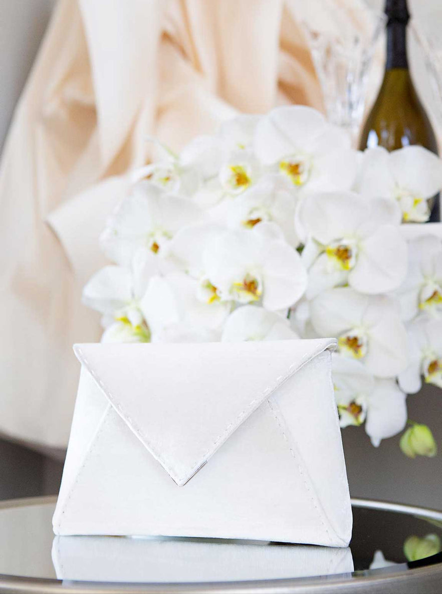 White orchids in a decorative container on a reflective surface with a blurred background